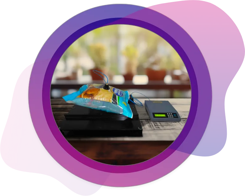 Blue food pouch undergoing pressure resistance test with electronic monitoring for packaging strength analysis